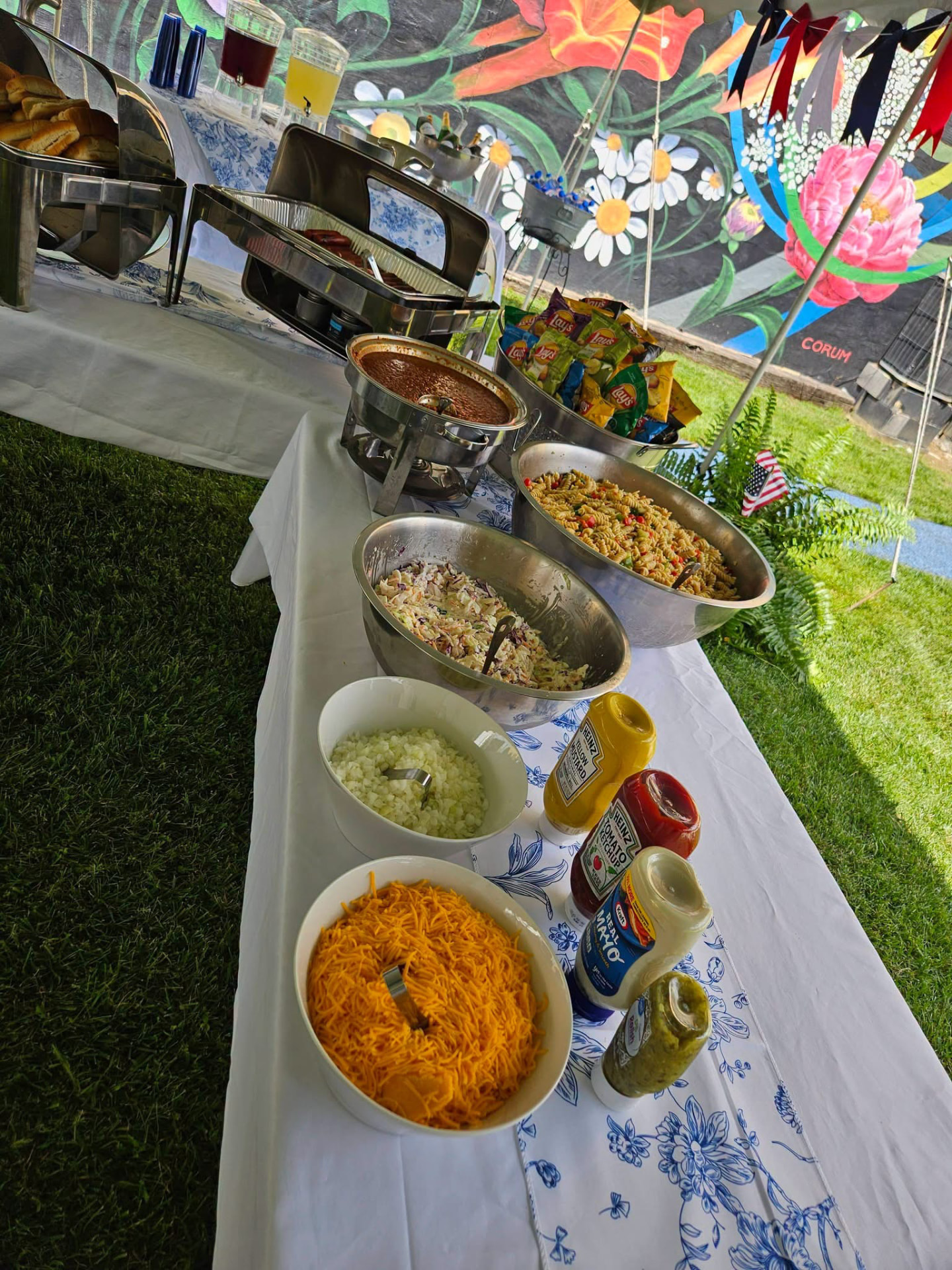 Cater It buffet line set up under a tent with pasta salad, slaw, chips and drinks